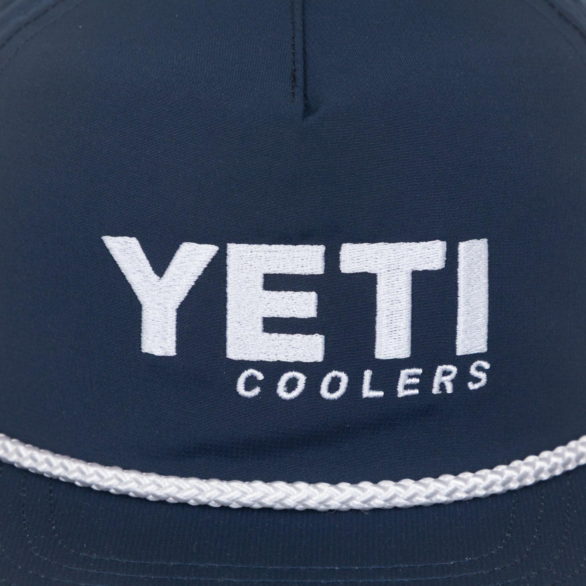 Close-up Navy blue cap with 'YETI Coolers' logo on a white background