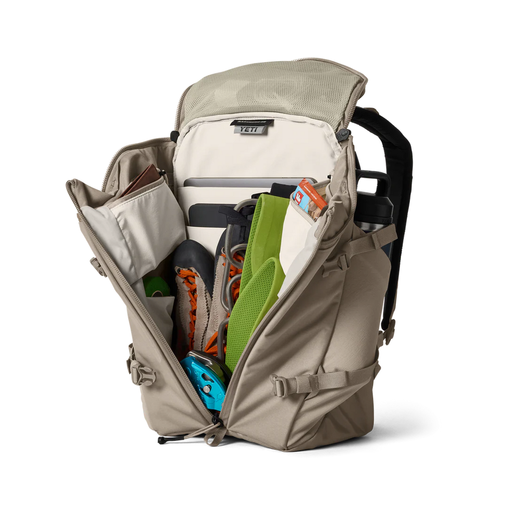 YETI Open beige backpack with various items on a white background