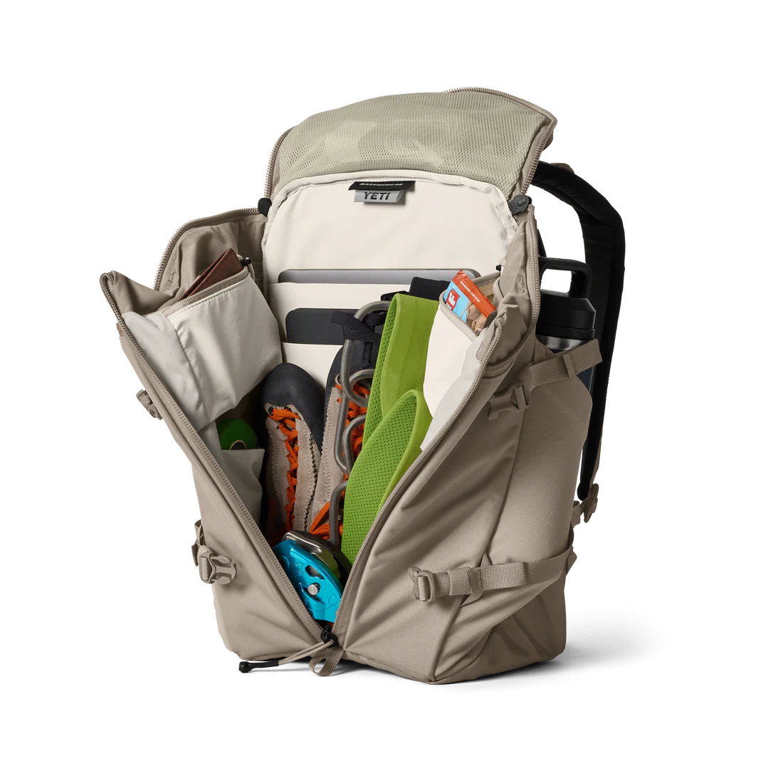 YETI Open beige backpack with various items on a white background