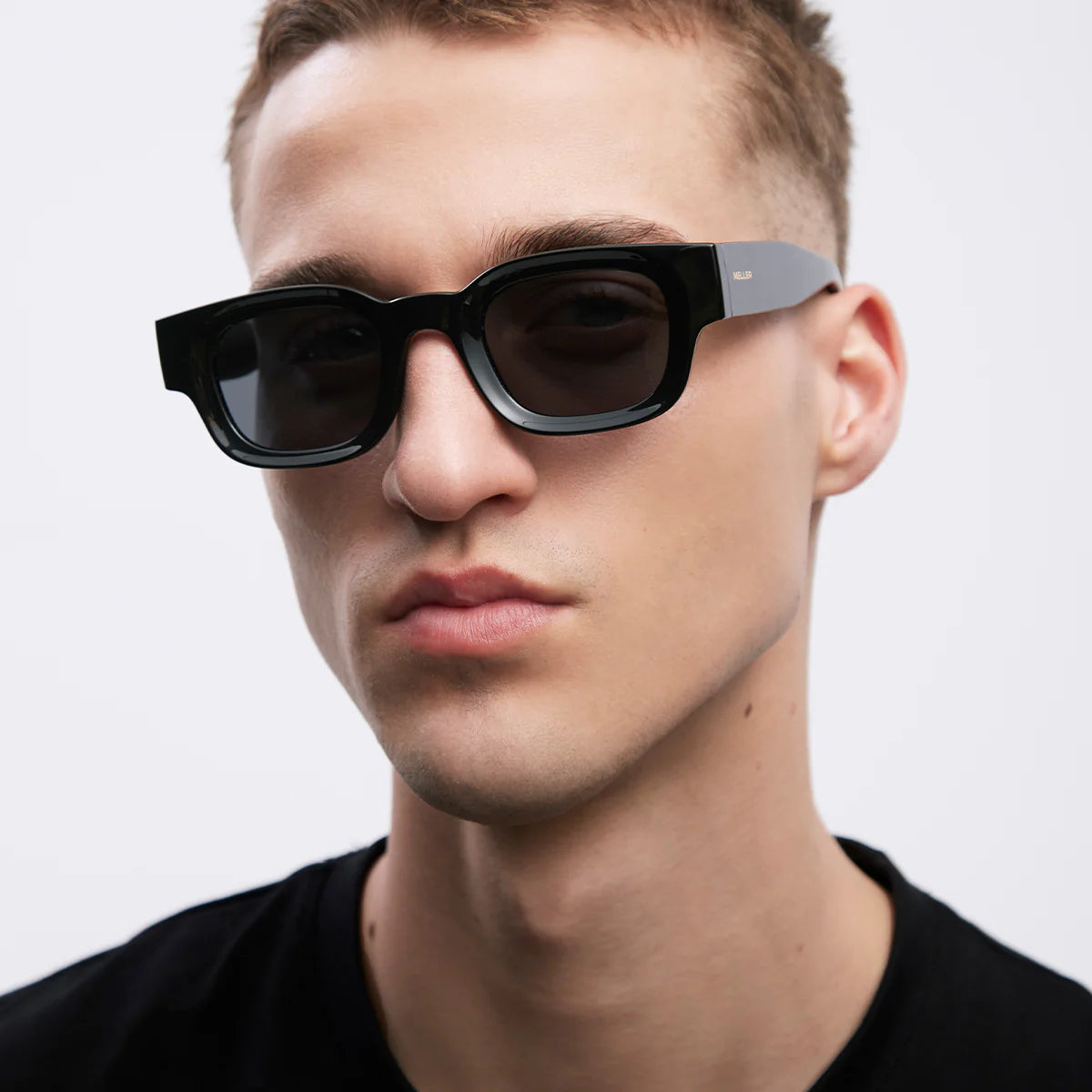 Man wearing meller black sunglasses with a neutral background